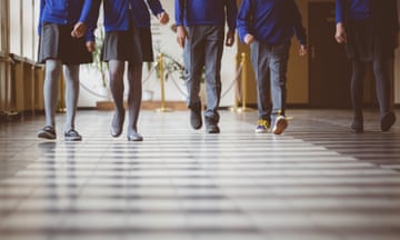 Cropped image of schoolchildren in uniform walking together in a row through corridor