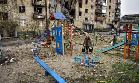 People carry bags from a damaged apartment block in Horenka village, near Kyiv.