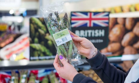 A customer holds up a pack of wonky vegetables in a Morrisons store