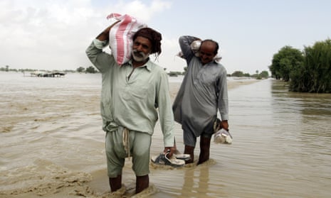 Two men carry food parcels after flooding in Rajanpur.