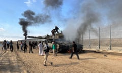 Hamas militants burn an Israeli armoured vehicle near a border fence