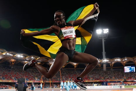 Jamaica’s Kimberly Williams holds her national flag as she celebrates winning the triple jump final.