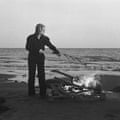 Kali Malone: Burning Song album artwork with a woman tending to a fire in front of the sea
