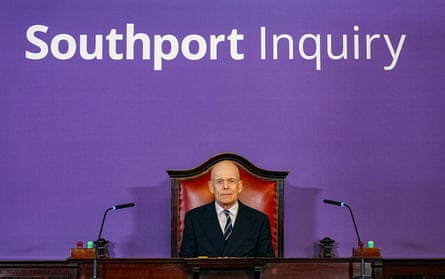 Adrian Fulford sat at a desk with the words ‘Southport Inquiry’ behind him in white on a purple wall