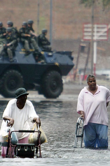As the National Guard patrols, Louis Jones, left, and Catherine McZeal help each other walk down flooded Poydras Street in New Orleans as they go to the Superdome 1 September 2005.
