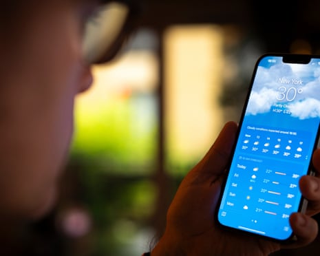 A man looks at his mobile device running the iOS Apple weather app