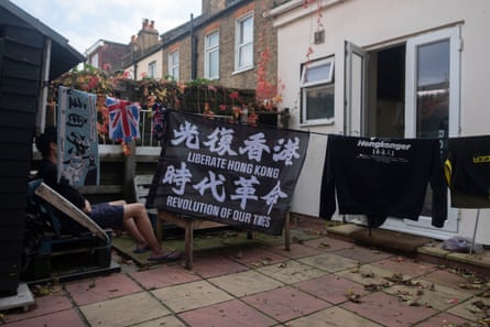 A washing line strung across a small paved yard and hung with a Hong Kong liberation banner and other flags and clothes