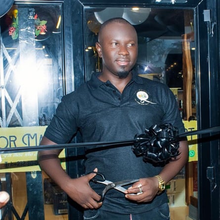 A man dressed in black cutting the ribbon outside a business