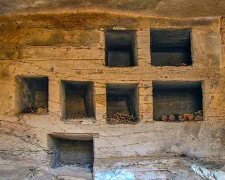 Seven square tombs cut out of yellow stone wall
