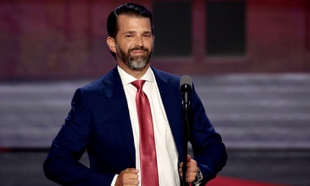 Donald Trump Jr smiles while talking in front of a microphone