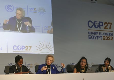 A group of panellists sitting at a table with a screen behind them