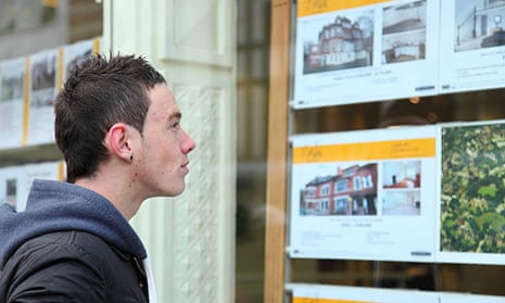 A first time buyer viewing houses in an estate agents window