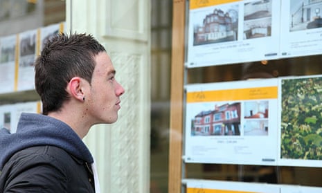 Young man viewing houses in an estate agent window