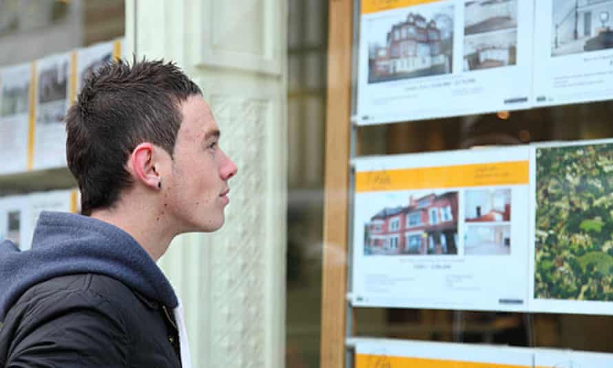 A young person looks at property in an estate agent's window