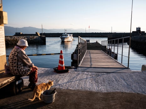 A cat and Mrs Kamimoto see off the last ferry leaving the island.