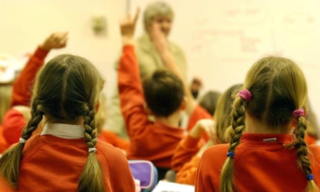 Primary schoolchildren hold up their hands in class