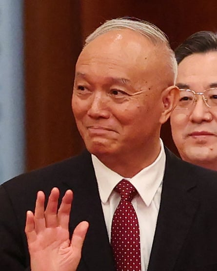 Cai Qi waves as he enters a hall. He is in his late 60s and is tall with thin, receding grey hair.