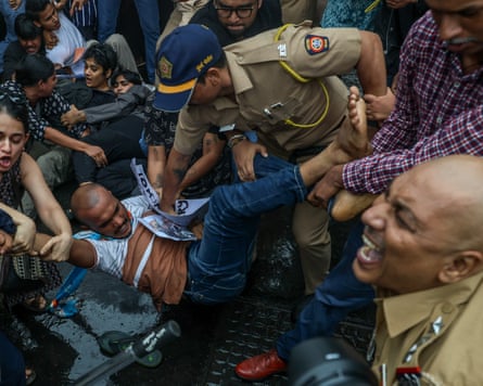 Police officers grappling with and detaining a demonstrator in Mumbai.