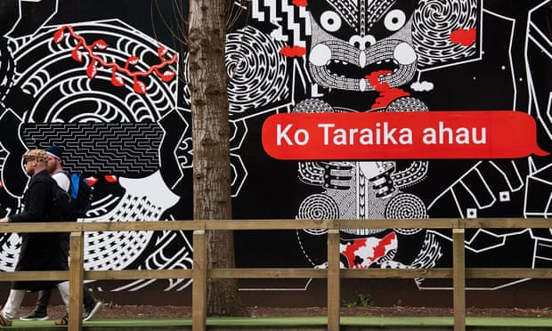 people walk past Maori language signs in Wellington on
