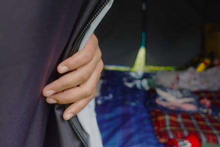 A woman’s hand holding back the door of a tent