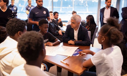 Sadiq Khan sits at a table with young people of all ethnicities at Chelsea FC