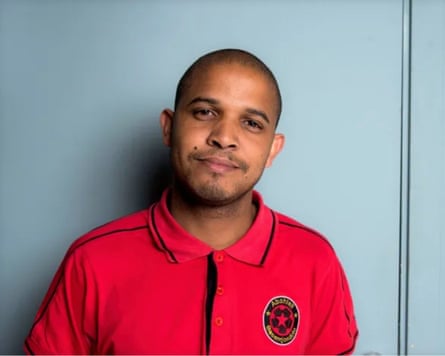 A man in a red T-shirt smiles at the camera.