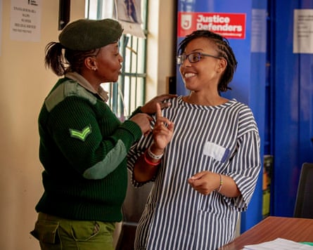 Two women, one wearing a prison guard’s uniform, share a joke.