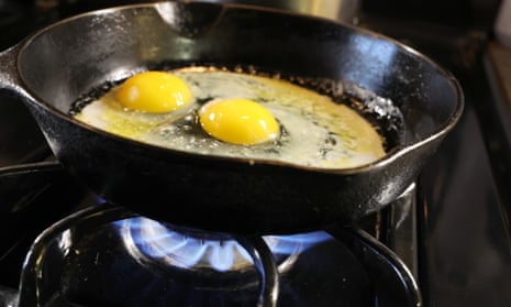 Eggs frying in cast iron over the flame of a gas stovetop
