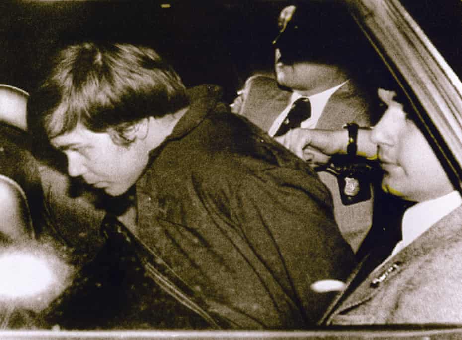 John Hinckley, left, is escorted by police on 30 March 1981 after shooting and seriously injuring Ronald Reagan.