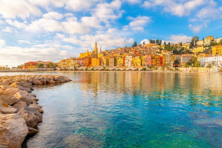 A town with yellow, orange and brown buildings behind blue coastal waters