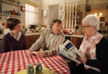 Cole sitting at a kitchen table reading a magazine, alongside her fictional son Roy Cropper and his wife, Hayley Cropper