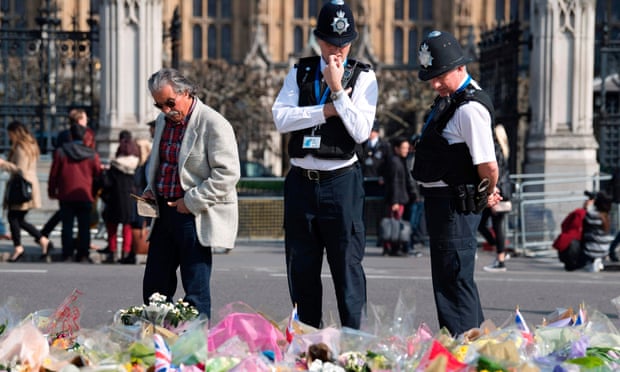 Police officers stop to look at floral tributes to the victims of the 22 March terror attack in Westminster.