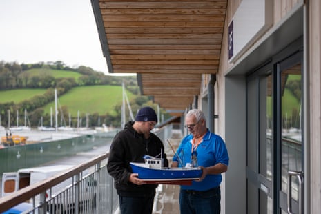 A young man and a older man study a model of a fishing trawler