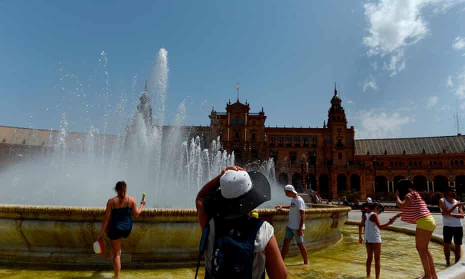 People refresh themselves in a fountain at Plaza de Espana, Seville, as temperatures climb to the mid-40s.
