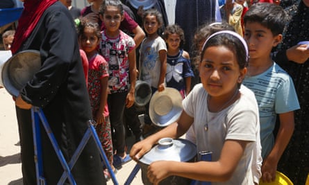 Children hold pans to collect hot food