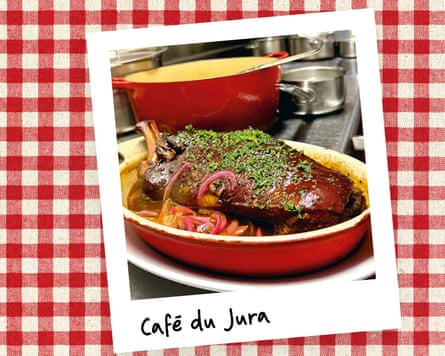 An instant photo of a dish of meat with a sauce on a counter, against a red gingham background.