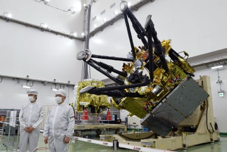 Two scientists in boiler suits and masks standing in front of spacecraft