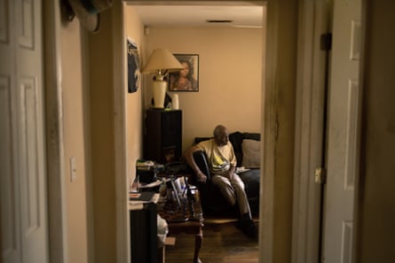 A man sits on a couch seen through a hallway