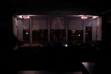 A couple have beers in a dark hotel lobby.