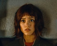 A young woman with short brown hair stares wide-eyed with a startled expression