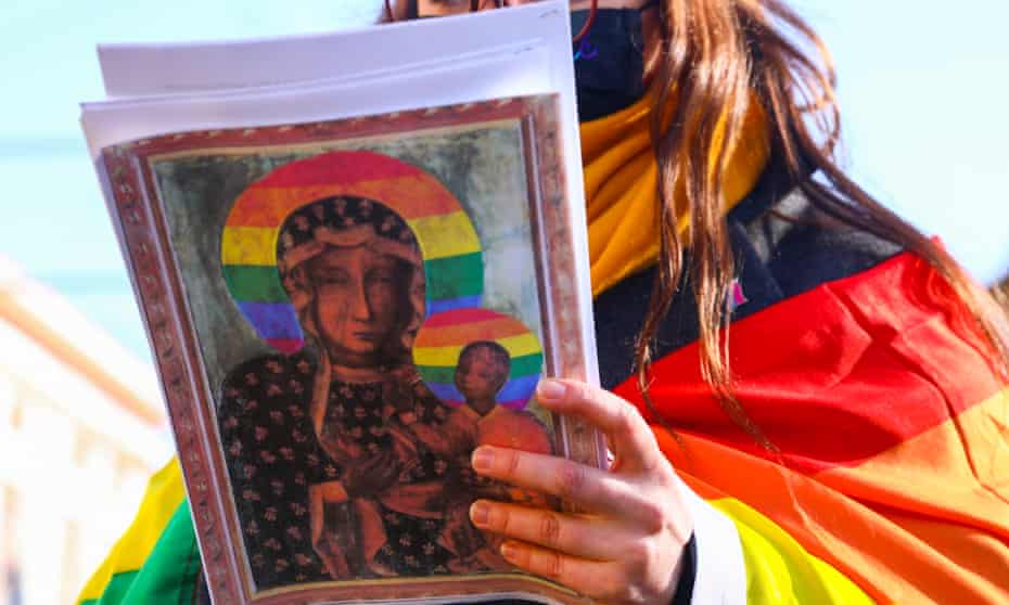 A protester in Krakow with a coy of the poster, which used rainbows as halos in an image of the Virgin Mary and the baby Jesus.