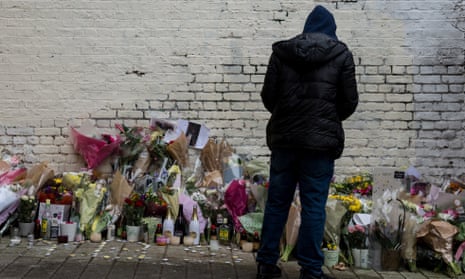 A young man looks at messages and flowers left at the scene in Hackney where 18 year old Israel Ogunsola was stabbed to death
