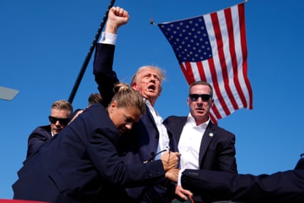 Republican presidential candidate former President Donald Trump is surrounded by US Secret Service agents after an assassination attempt at a campaign rally in Butler, Pa., Saturday, July 13, 2024