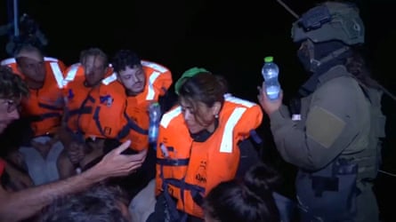 An Israeli soldier passes water to those onboard the Gaza-bound British-flagged yacht