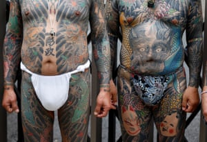 The tattooed torsos and thighs of two men wearing loincloths