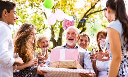 An older gentlemen festooned with gifts and presents at a garden party