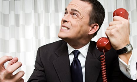 angry man holding a red telephone receiver