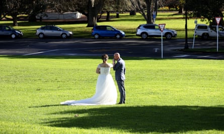 A bride and groom pose for a photo in an Auckland park
