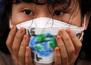 Seoul, South Korea: a girl wears a face mask with a drawing of Earth during a global climate protest near the presidential office