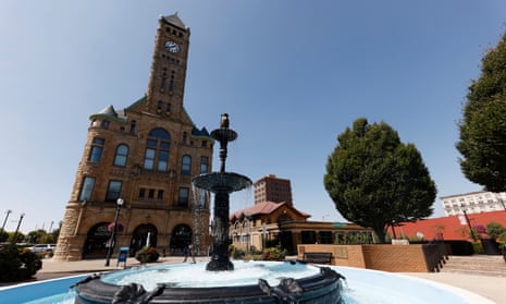 Wrought iron fountain with blue bowl, across square from limestone building.